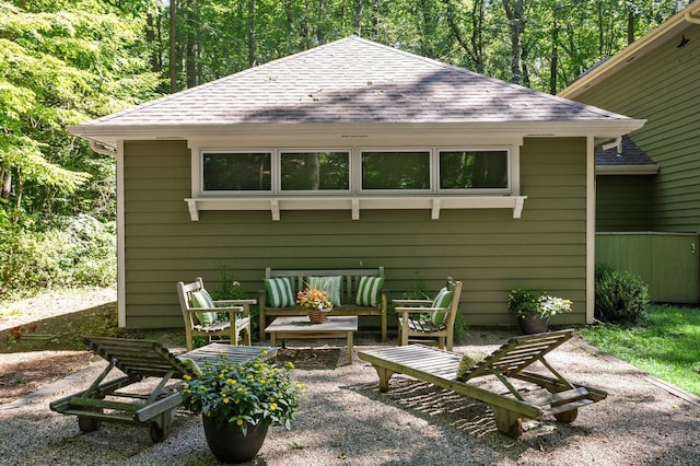 rear view of property with roof with shingles, a patio, and an outdoor hangout area