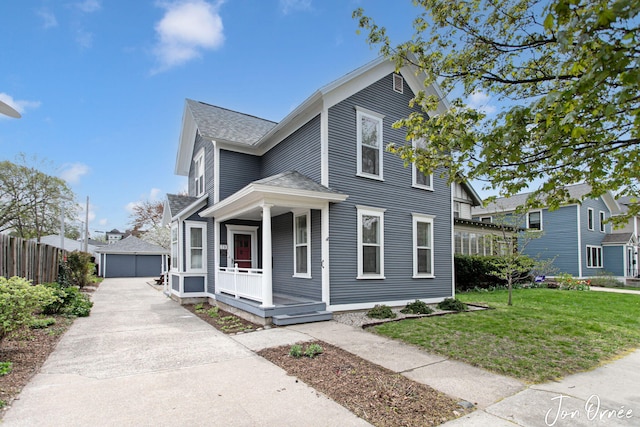 view of front facade with covered porch, roof with shingles, a garage, an outdoor structure, and a front lawn