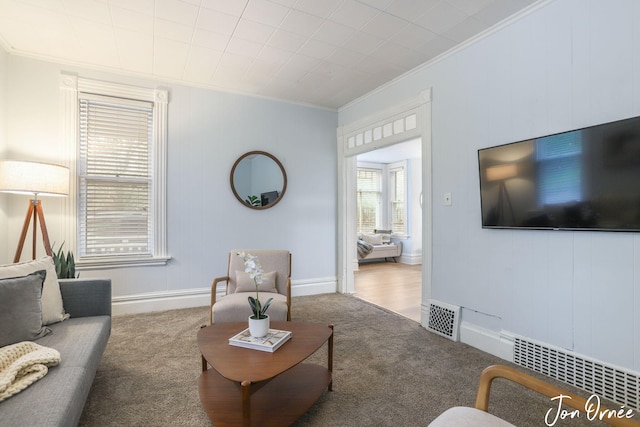 living area with crown molding, baseboards, visible vents, and carpet
