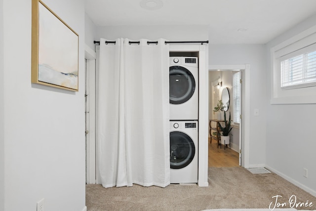 laundry area featuring laundry area, stacked washing maching and dryer, baseboards, and carpet