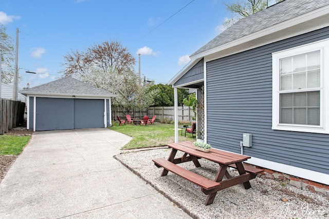 view of patio featuring a garage, a fenced backyard, and an outbuilding