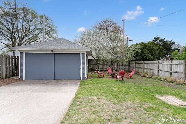 view of yard with a garage, an outdoor structure, a fire pit, and fence private yard