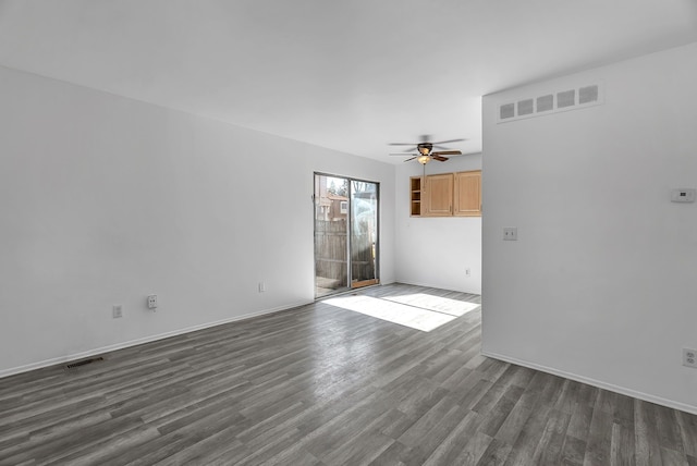 unfurnished room featuring ceiling fan, dark wood-style floors, and visible vents