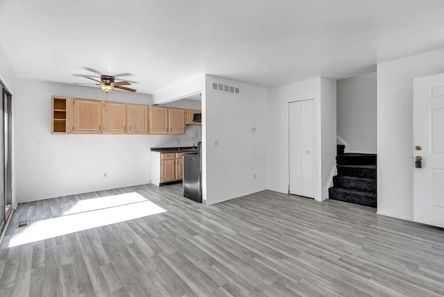 unfurnished living room with ceiling fan, visible vents, baseboards, and stairway