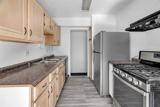 kitchen with dark countertops, a sink, light brown cabinets, stainless steel range with gas cooktop, and under cabinet range hood