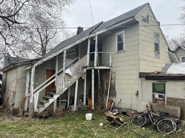 rear view of house with stairs and a chimney