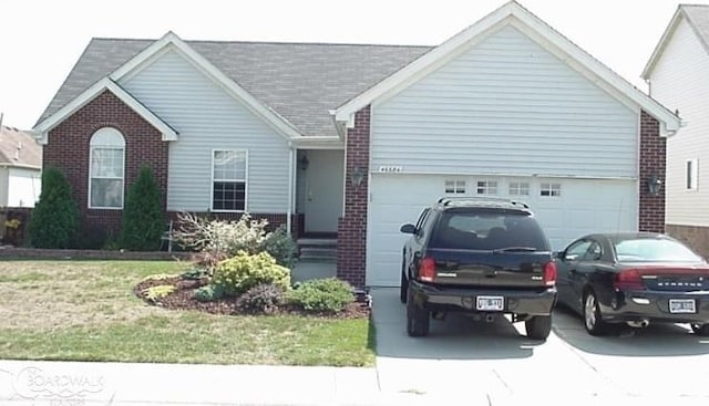 ranch-style home with an attached garage, driveway, a front lawn, and brick siding