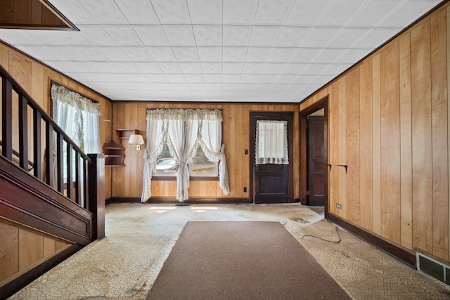 entryway with wood walls, carpet, baseboards, and visible vents