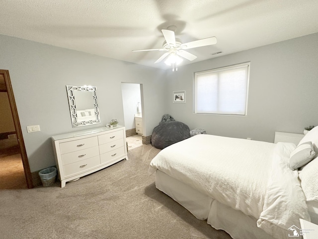 bedroom featuring visible vents, ensuite bath, ceiling fan, and light colored carpet