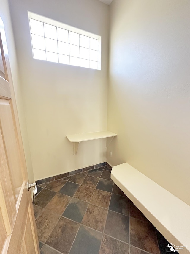 mudroom featuring a healthy amount of sunlight, baseboards, and stone finish floor