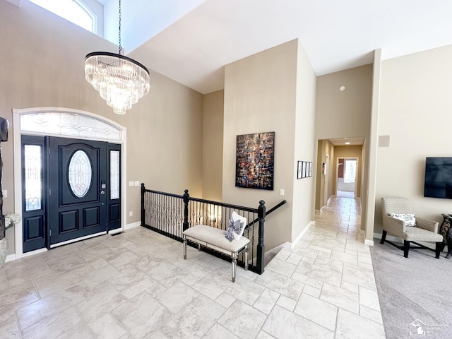 entryway featuring stone tile flooring, baseboards, a high ceiling, and a healthy amount of sunlight