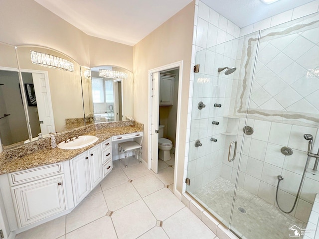 bathroom featuring vanity, toilet, tile patterned floors, and a stall shower