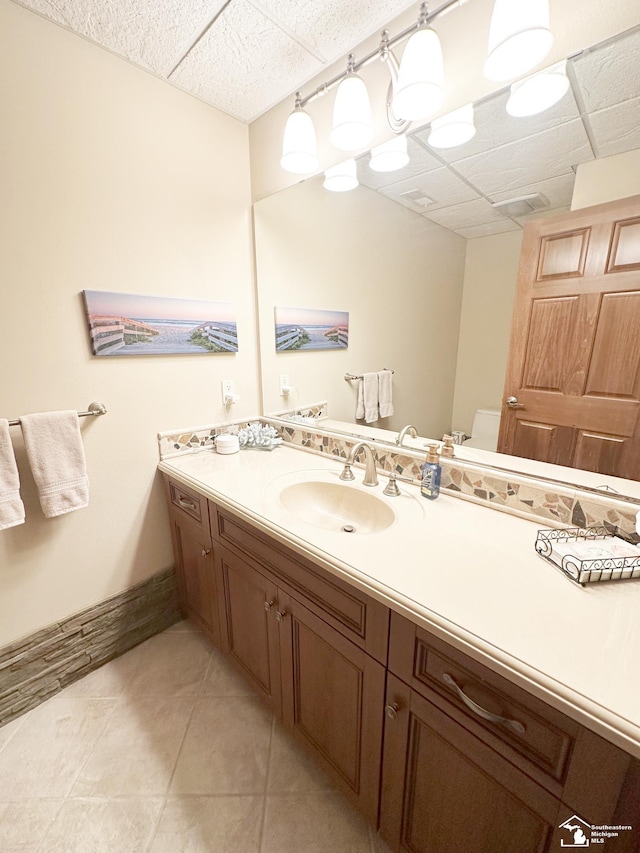 bathroom with tile patterned floors, a paneled ceiling, and vanity