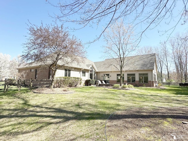 back of property featuring a yard, brick siding, and fence
