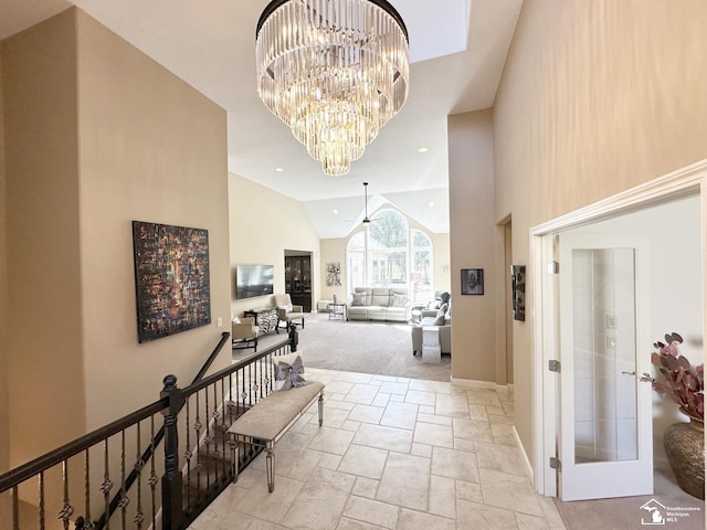 hall featuring high vaulted ceiling, baseboards, stone tile floors, and a notable chandelier