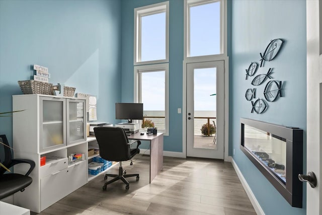 home office featuring baseboards, a high ceiling, and wood finished floors