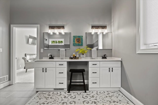 full bath featuring double vanity, baseboards, visible vents, and a sink