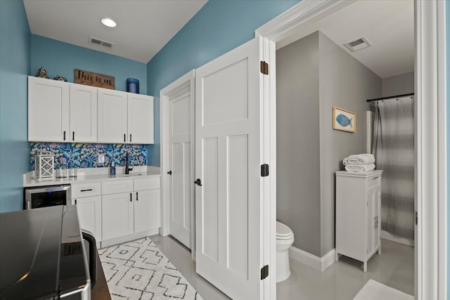 kitchen with light countertops, white cabinets, visible vents, and decorative backsplash