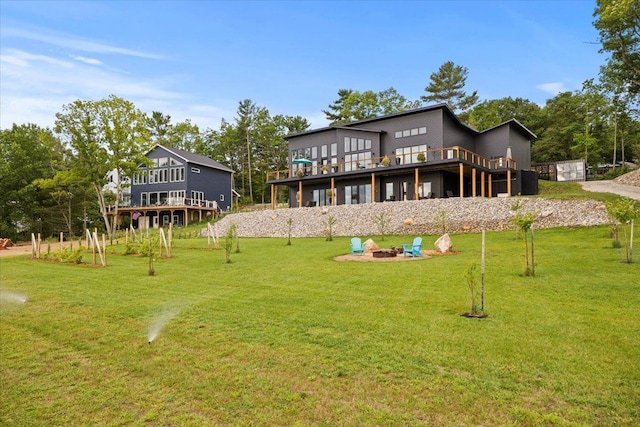 rear view of property with a lawn, a fire pit, and a deck