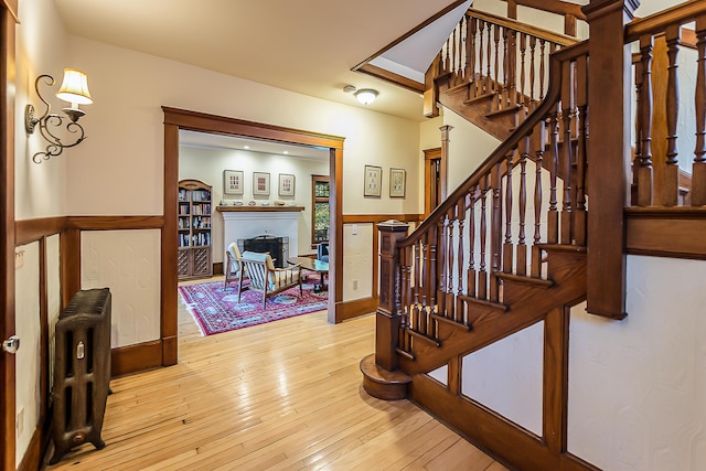 staircase with radiator, a fireplace, and hardwood / wood-style flooring