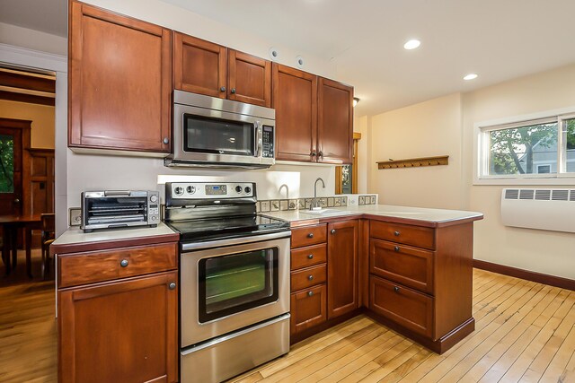 kitchen with a sink, light countertops, a toaster, a peninsula, and stainless steel appliances