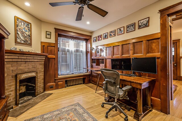 office featuring a fireplace, recessed lighting, built in desk, a ceiling fan, and light wood-style flooring