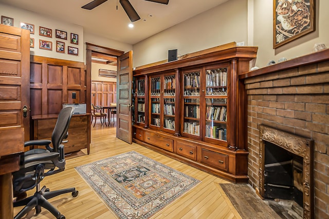 home office with wood-type flooring, a ceiling fan, a brick fireplace, and recessed lighting