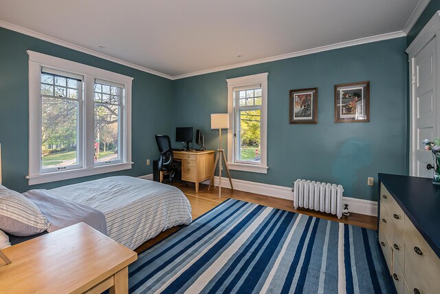 bedroom with baseboards, ornamental molding, radiator heating unit, and wood finished floors