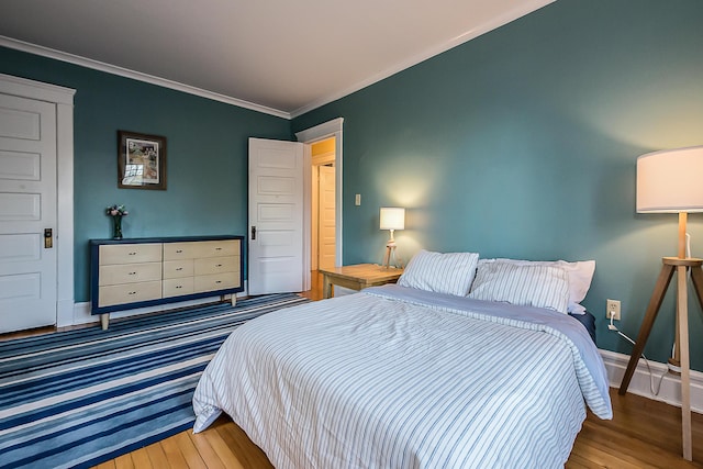 bedroom featuring baseboards, ornamental molding, and wood finished floors