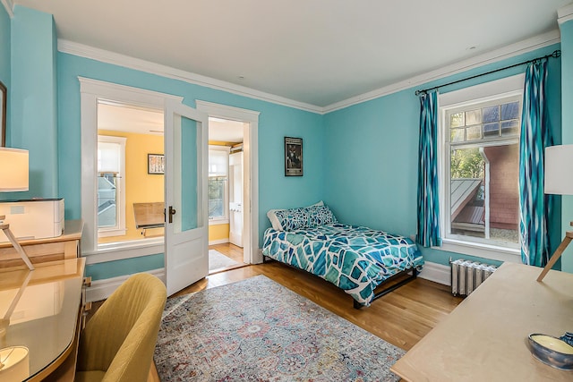 bedroom featuring baseboards, ornamental molding, radiator heating unit, and wood finished floors