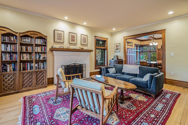 living room with crown molding, an inviting chandelier, a fireplace, wood-type flooring, and baseboards