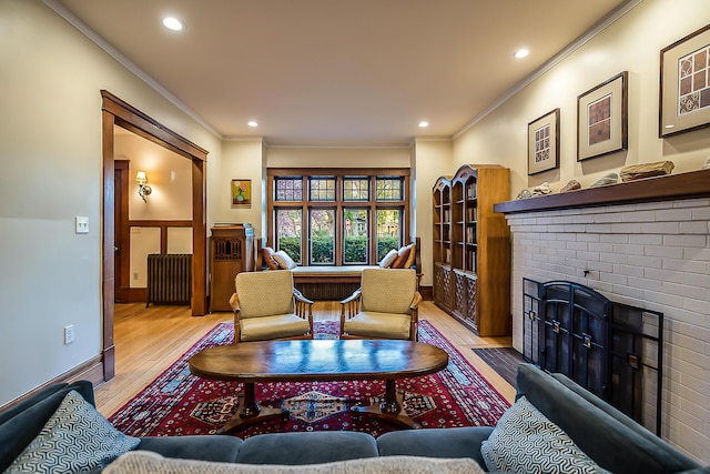 living room featuring a brick fireplace, wood finished floors, radiator, ornamental molding, and recessed lighting