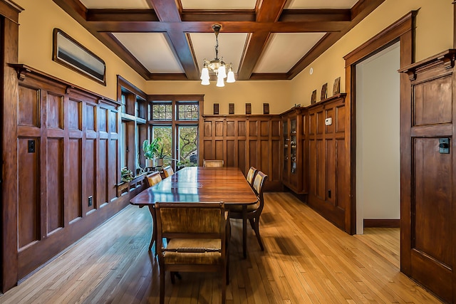 dining area with light wood-style floors, coffered ceiling, a chandelier, and beamed ceiling