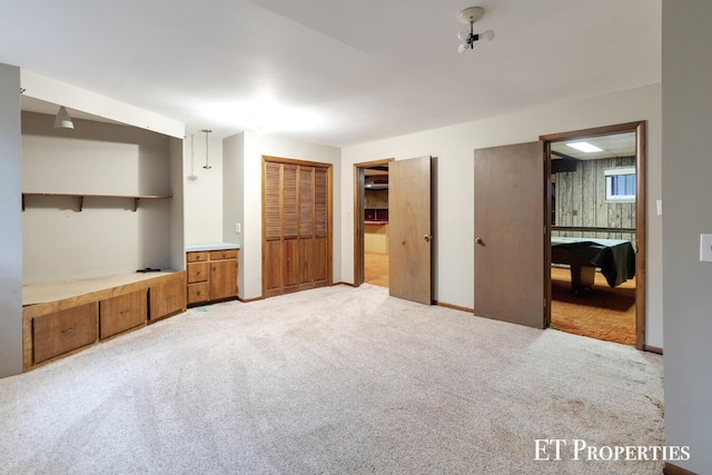 unfurnished bedroom featuring light colored carpet, ensuite bathroom, and two closets