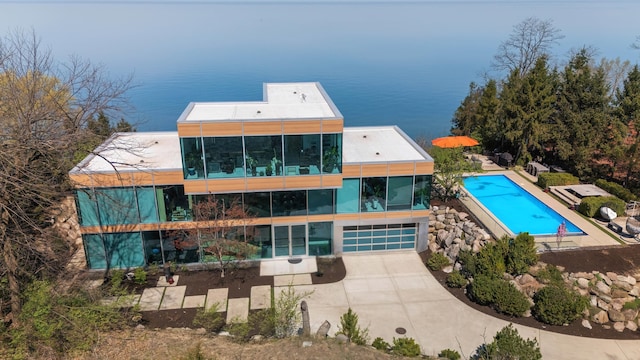 rear view of house with a garage, a water view, and an outdoor pool