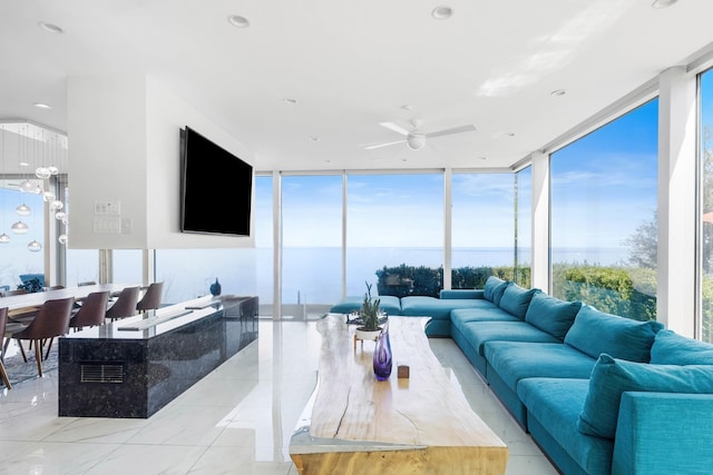 living area with ceiling fan and a wall of windows