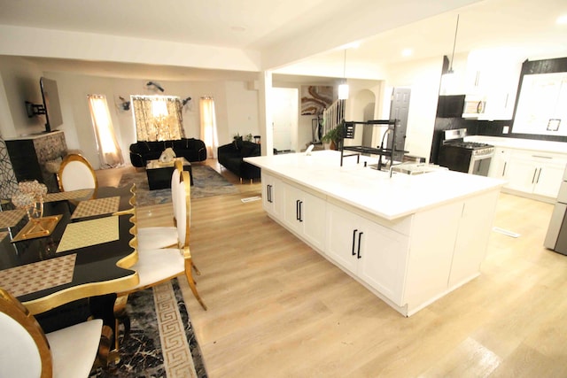 17150 Santa Barbara Dr, Detroit, MI 48221 - kitchen with appliances with stainless steel finishes, an island with sink, white cabinetry, light wood finished floors, and a sink