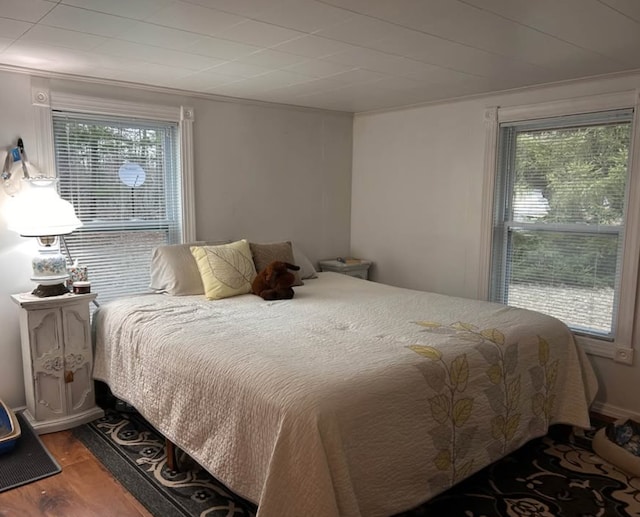 bedroom with wood finished floors and ornamental molding