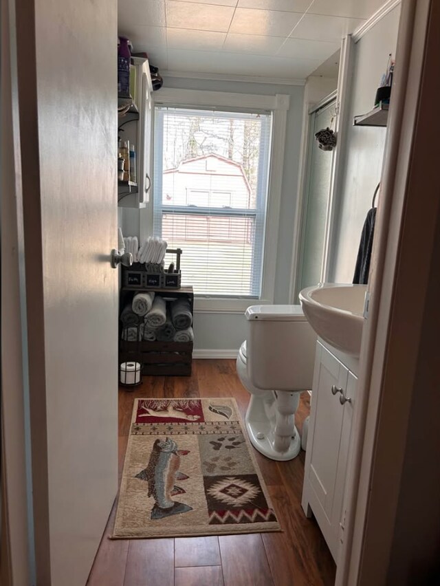 full bath with toilet, a shower with door, wood finished floors, and vanity