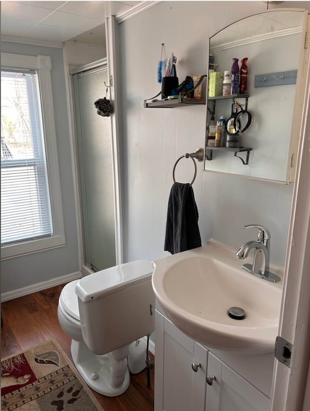 bathroom featuring vanity, ornamental molding, wood finished floors, toilet, and a stall shower