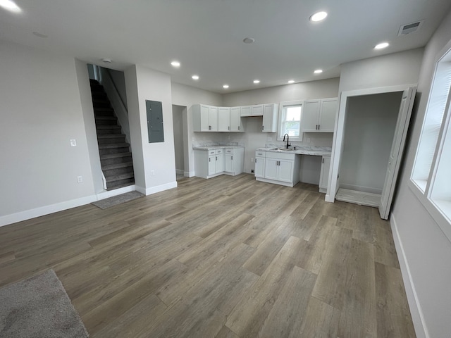 171 Davis St, Wyandotte, MI 48192 - kitchen with electric panel, white cabinets, baseboards, light wood finished floors, and recessed lighting