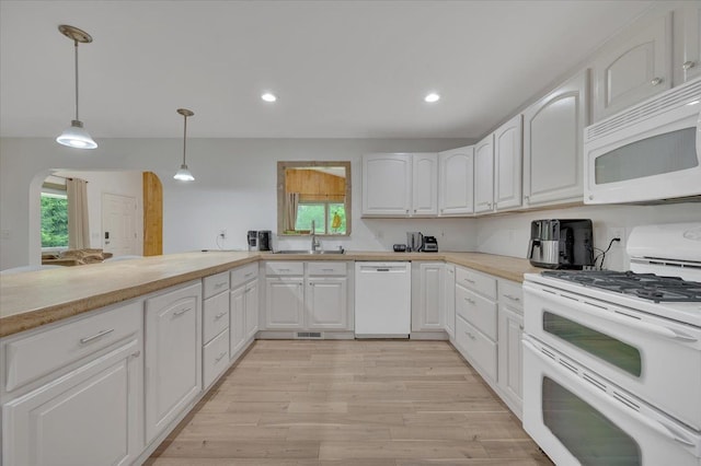 kitchen with white appliances, a sink, light wood-style floors, pendant lighting, and white cabinetry
