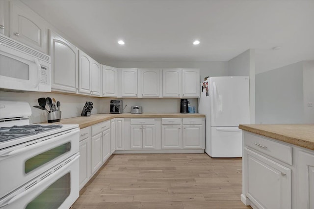 kitchen with white appliances, light wood-type flooring, white cabinetry, recessed lighting, and light countertops