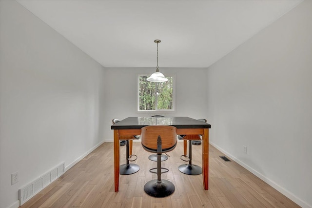 dining area featuring baseboards, light wood-style floors, and a desk