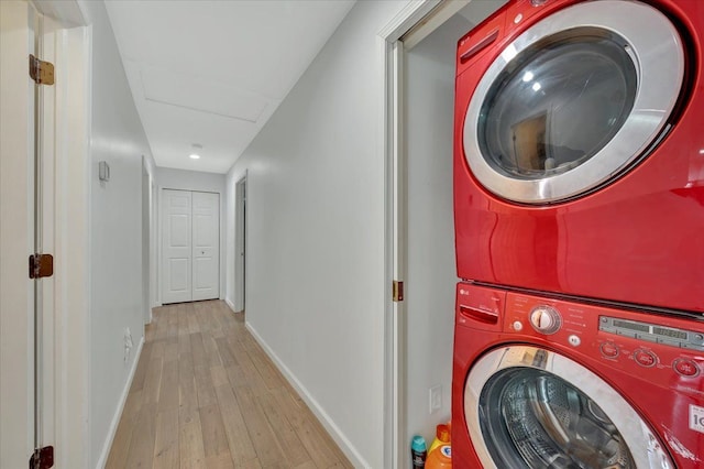 laundry room featuring stacked washer / drying machine, hardwood / wood-style flooring, baseboards, and recessed lighting
