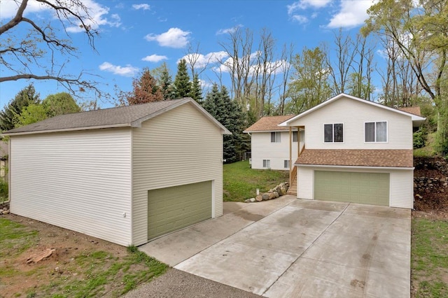view of home's exterior with a detached garage, concrete driveway, and a shingled roof