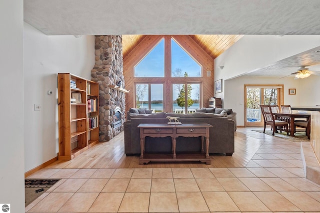 living area featuring a ceiling fan, a water view, light tile patterned floors, and high vaulted ceiling