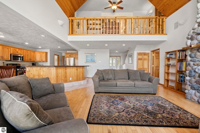 living area with high vaulted ceiling, ceiling fan, recessed lighting, and light wood-style flooring