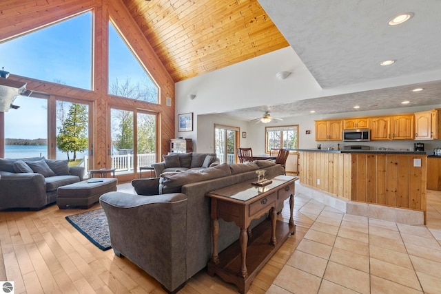 living room featuring a water view, high vaulted ceiling, recessed lighting, and light wood finished floors