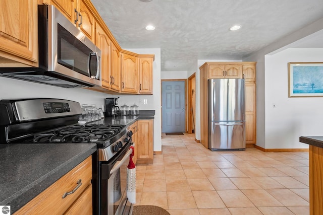 kitchen with dark countertops, light tile patterned floors, baseboards, stainless steel appliances, and recessed lighting